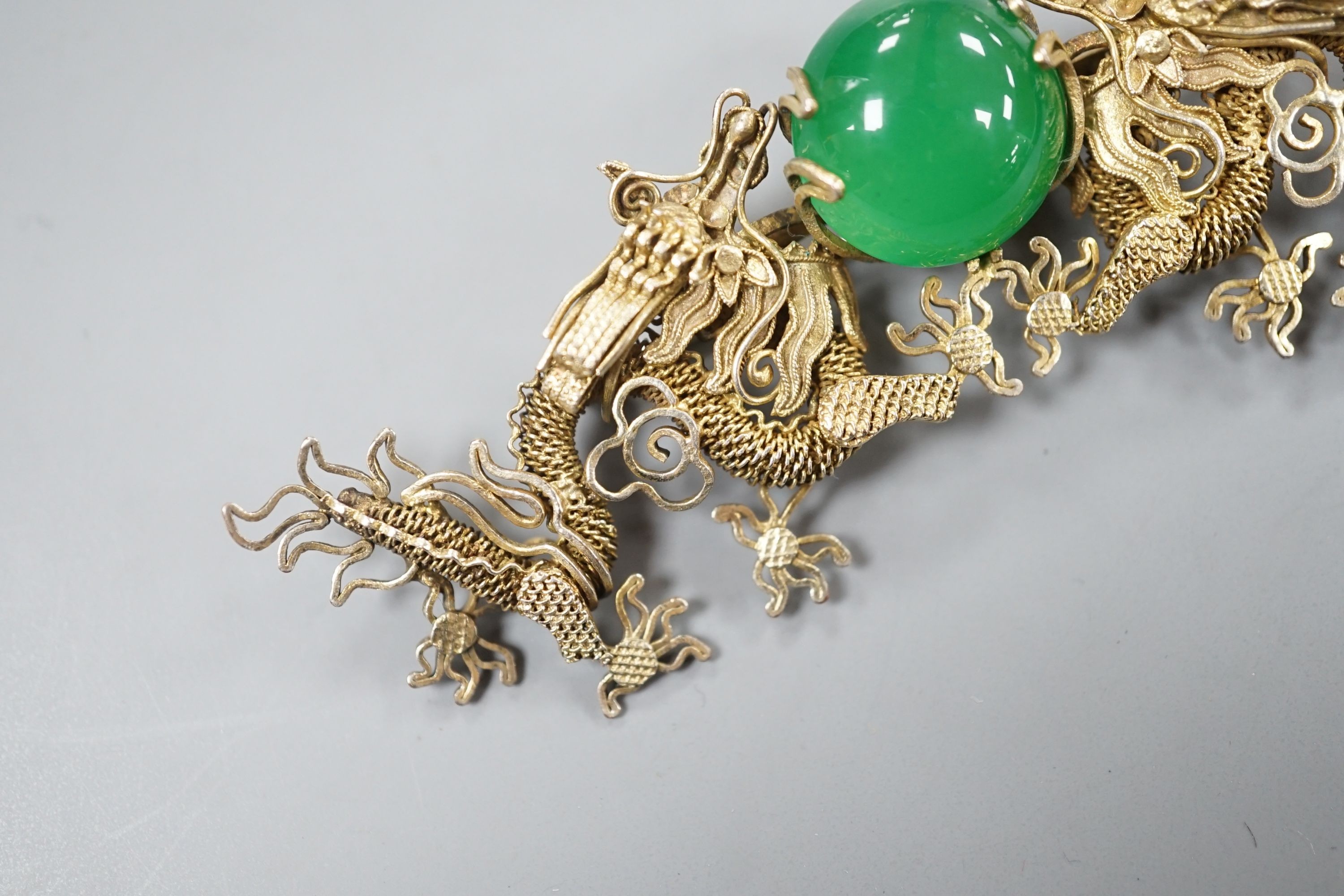 A Chinese gilt white metal and green cabochon stone set filigree dragon brooch, 88mm.